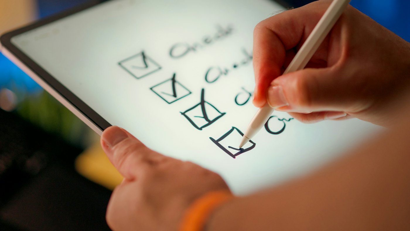 A hand checking items off a list on a tablet