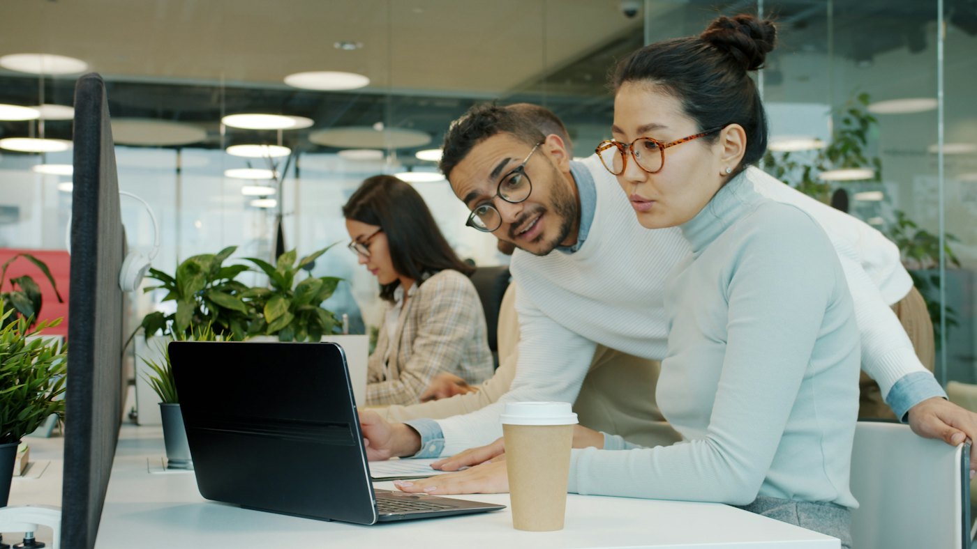 Two colleagues reviewing work together on a laptop in a modern office